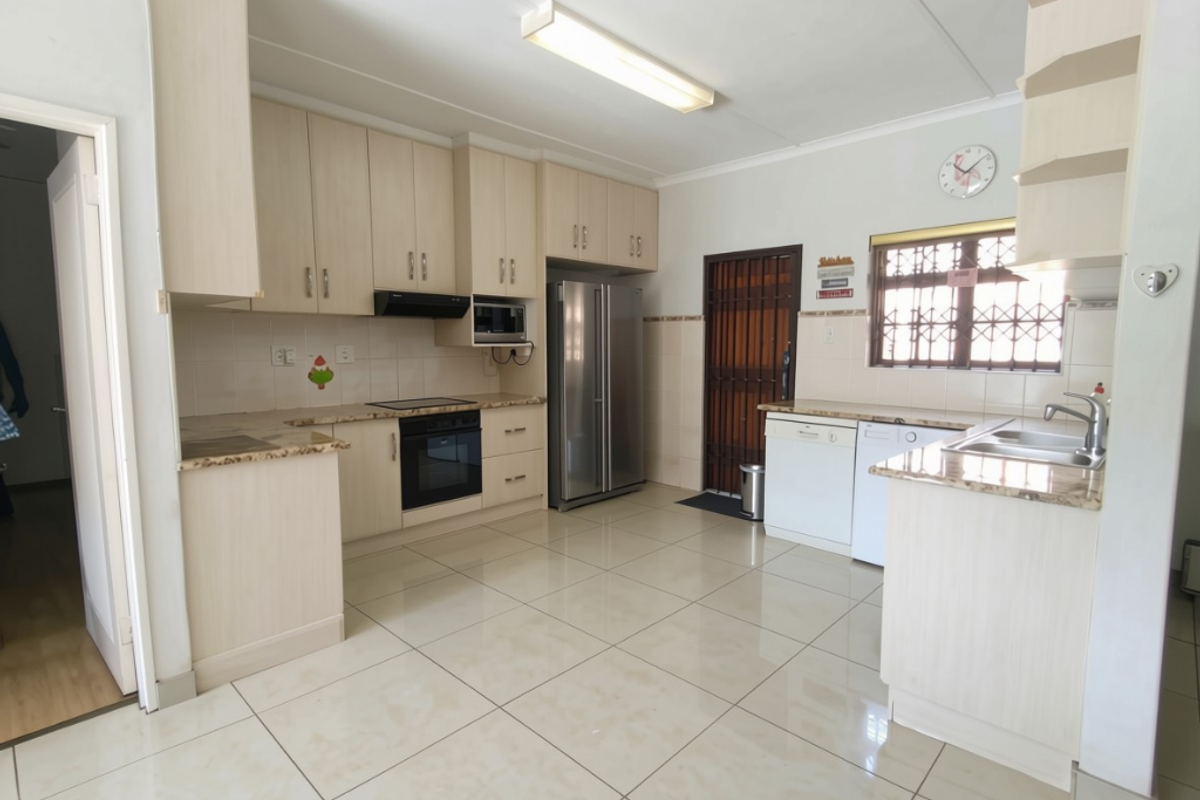 A functional kitchen featuring light-toned cabinetry, granite countertops, integrated appliances, and tiled flooring, providing a clean and practical workspace.