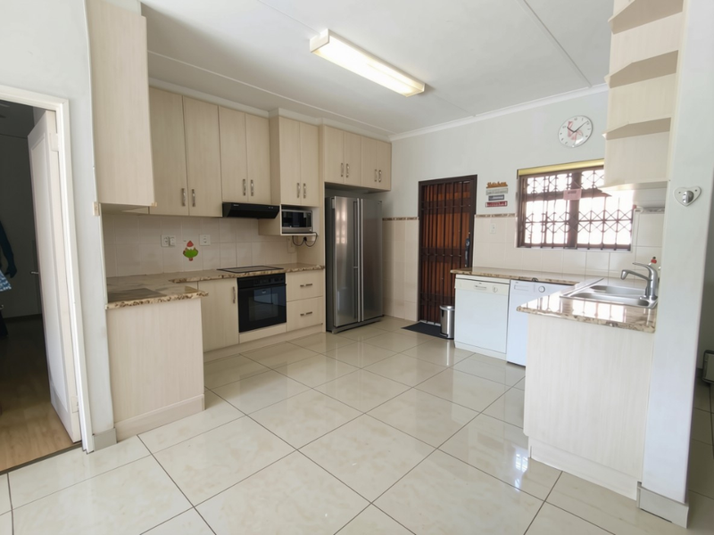 A functional kitchen featuring light-toned cabinetry, granite countertops, integrated appliances, and tiled flooring, providing a clean and practical workspace.