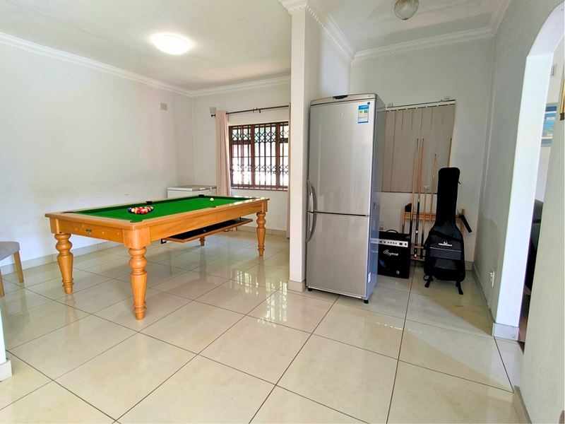A tiled living area featuring decorative cornice and security bars on the windows, currently utilized as a recreational space.