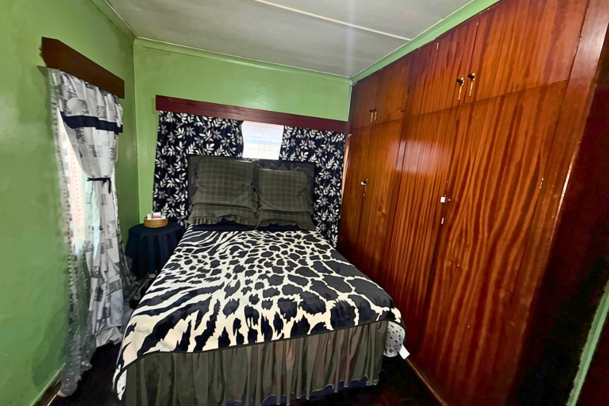 A bedroom featuring built-in wooden wardrobes and dark wooden flooring, offering a functional space with potential for modern updates.
