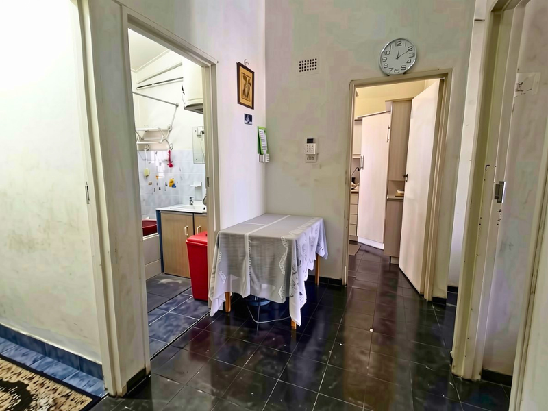 A functional hallway connecting multiple rooms, featuring dark tiled flooring and access to a bathroom and kitchen area.