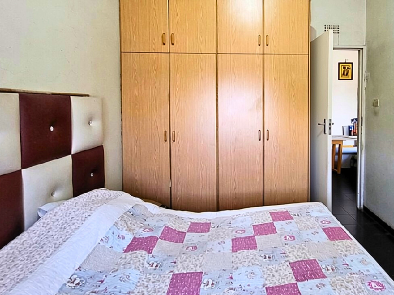 A bedroom featuring floor-to-ceiling built-in wooden cupboards providing ample storage space.
