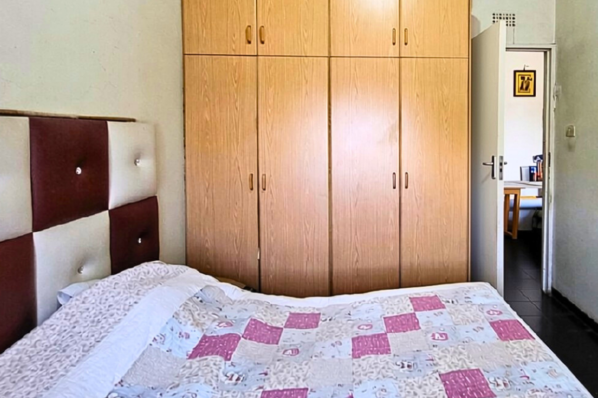 A bedroom featuring floor-to-ceiling built-in wooden cupboards providing ample storage space.