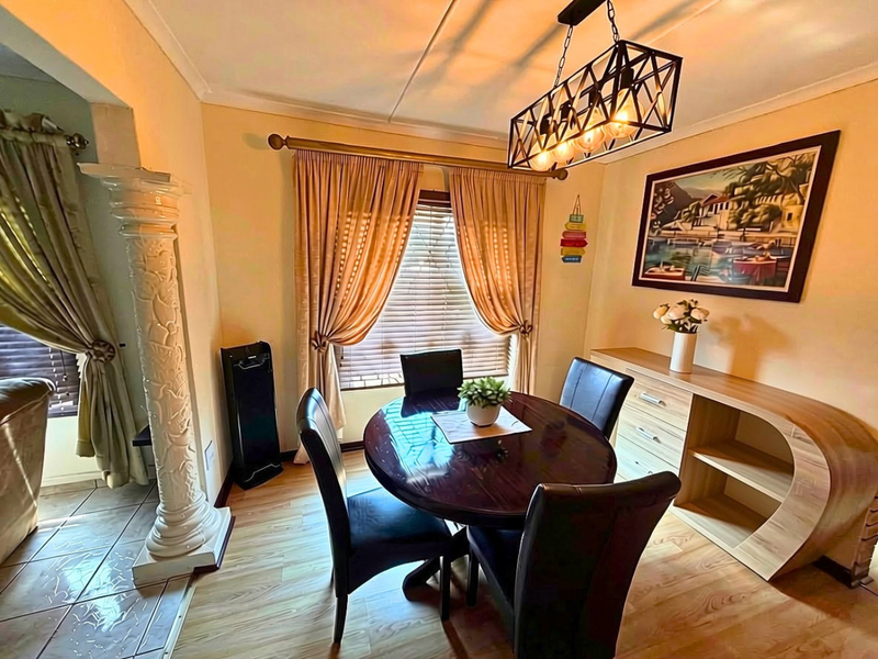 A dining area featuring laminate flooring, a decorative pillar, and a modern pendant light fixture, creating a warm and inviting space.