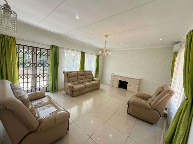 Spacious living room featuring large format floor tiles, a stone-clad fireplace, recessed lighting, and direct access to the exterior through a security gate.