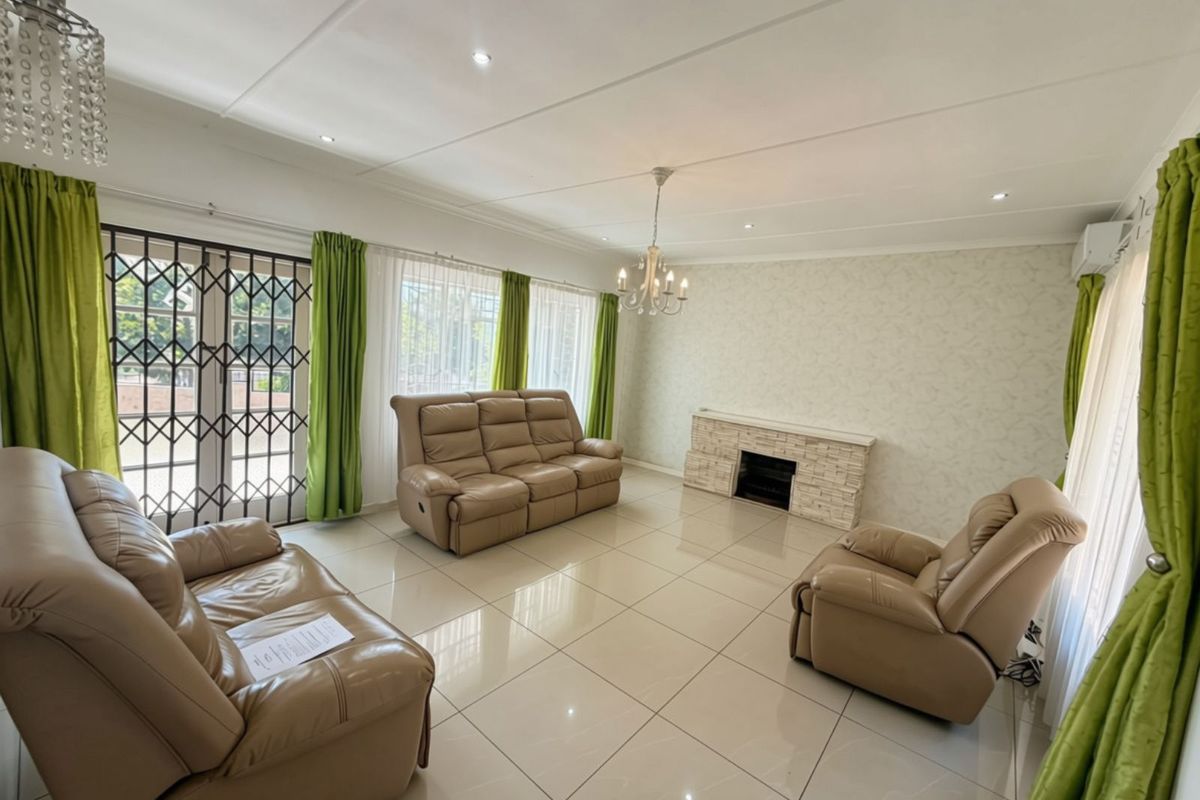 Spacious living room featuring large format floor tiles, a stone-clad fireplace, recessed lighting, and direct access to the exterior through a security gate.