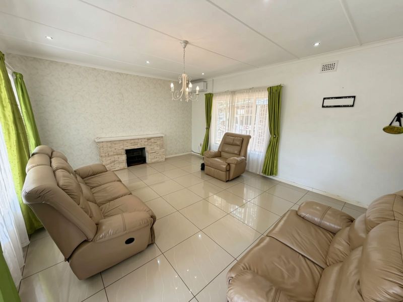 Spacious living room featuring large format floor tiles, a stone-clad fireplace, and modern recessed lighting, offering a bright and neutral foundation for living.