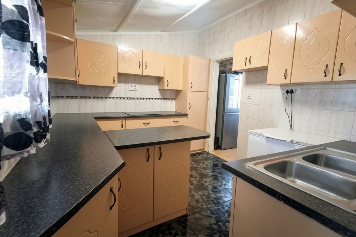 Functional kitchen featuring laminate cabinetry, dark countertops, double bowl stainless steel sink, and ceramic tile finishes throughout.