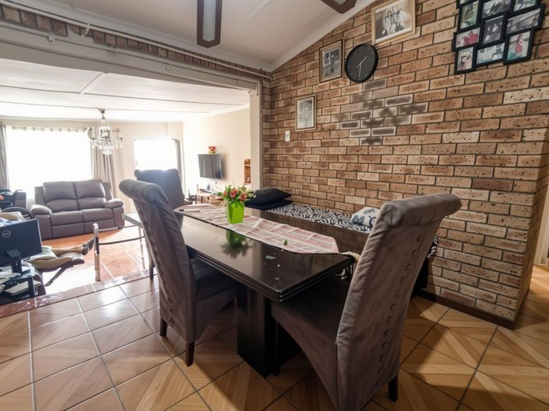 Open plan living and dining area featuring a distinctive exposed brick feature wall and tiled flooring throughout.