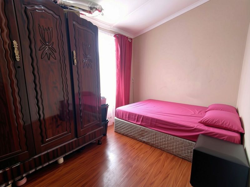 A bedroom featuring laminate flooring and coved ceiling details, providing a functional space with natural light.