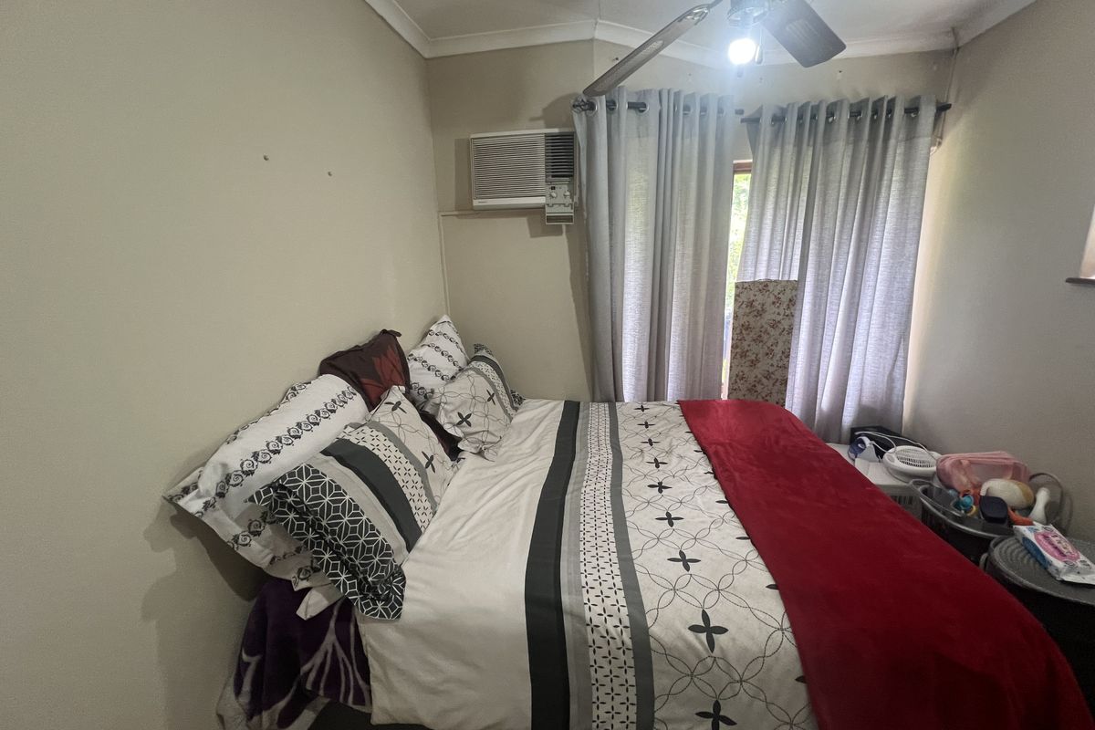 A bedroom featuring a ceiling fan and a wall-mounted air conditioning unit, providing essential climate control and ventilation.