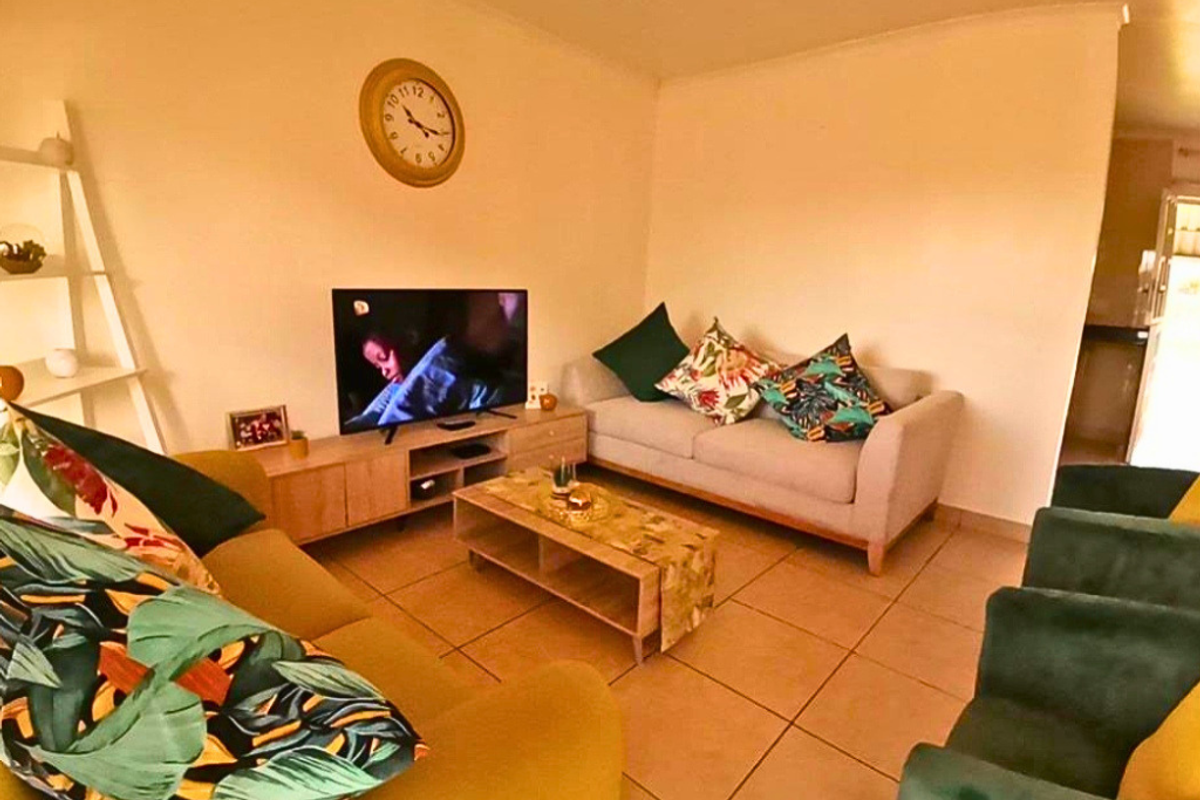 A comfortable living room featuring tiled flooring and a neutral wall finish, providing a functional space for relaxation.