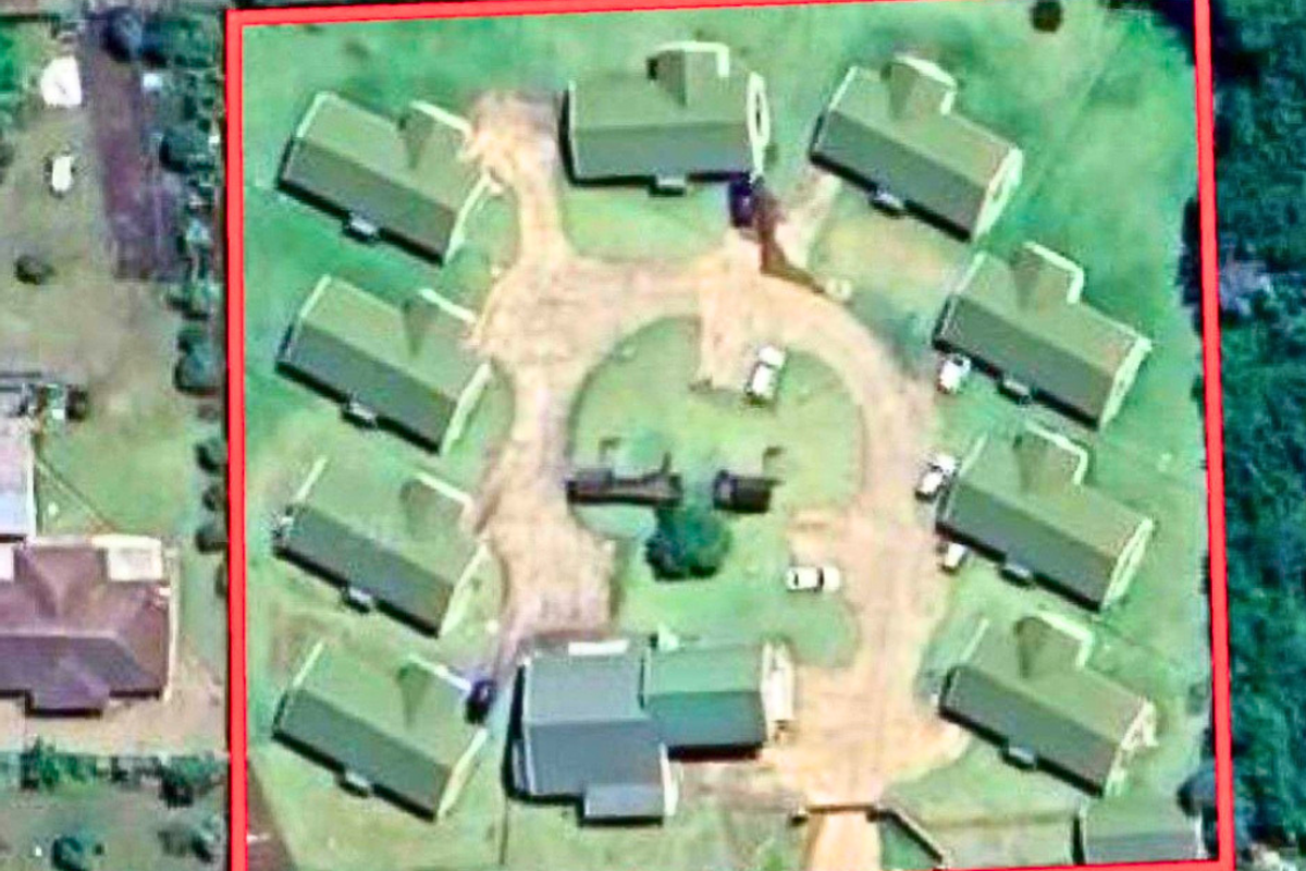 Aerial view of a residential complex featuring multiple detached units arranged around a central driveway and landscaped grounds.
