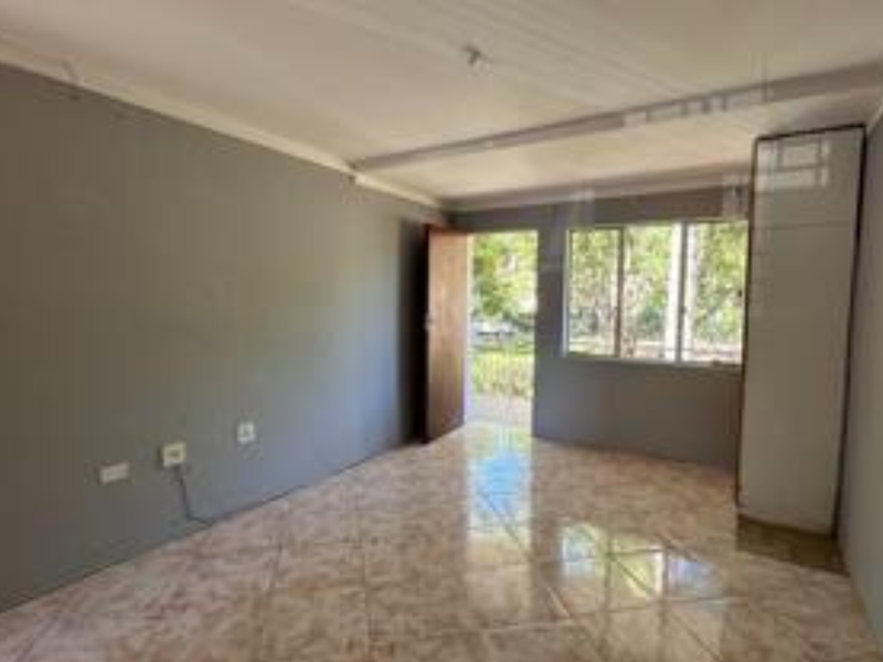 An empty bedroom featuring tiled flooring, a built-in cupboard, and direct access to the exterior through a door.