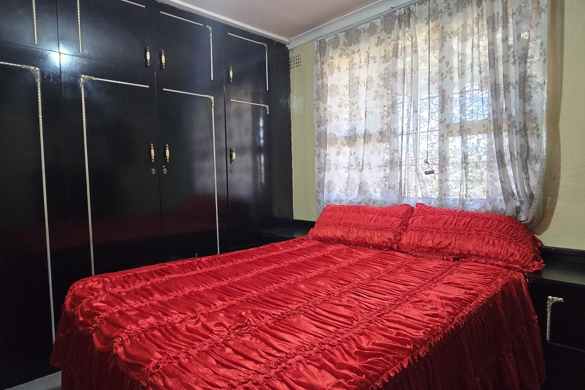 A bedroom featuring extensive floor-to-ceiling built-in cabinetry and a window with security bars.