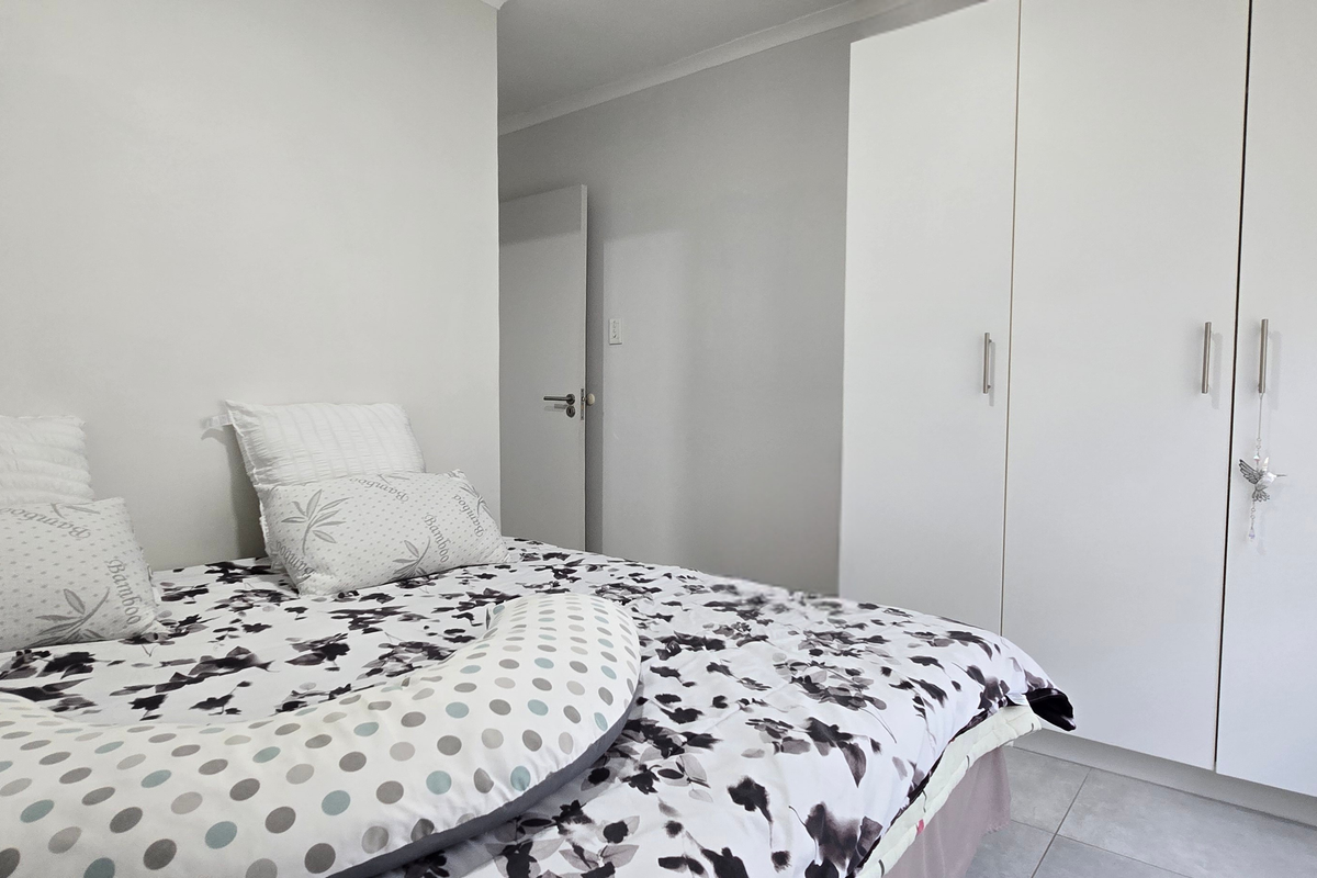 A bright bedroom featuring built-in white cabinetry and neutral tiled flooring, offering a clean and functional living space.