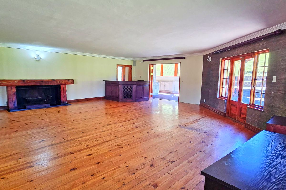Spacious living room featuring polished timber flooring, a built-in fireplace with a timber mantel, and a custom built-in bar area.