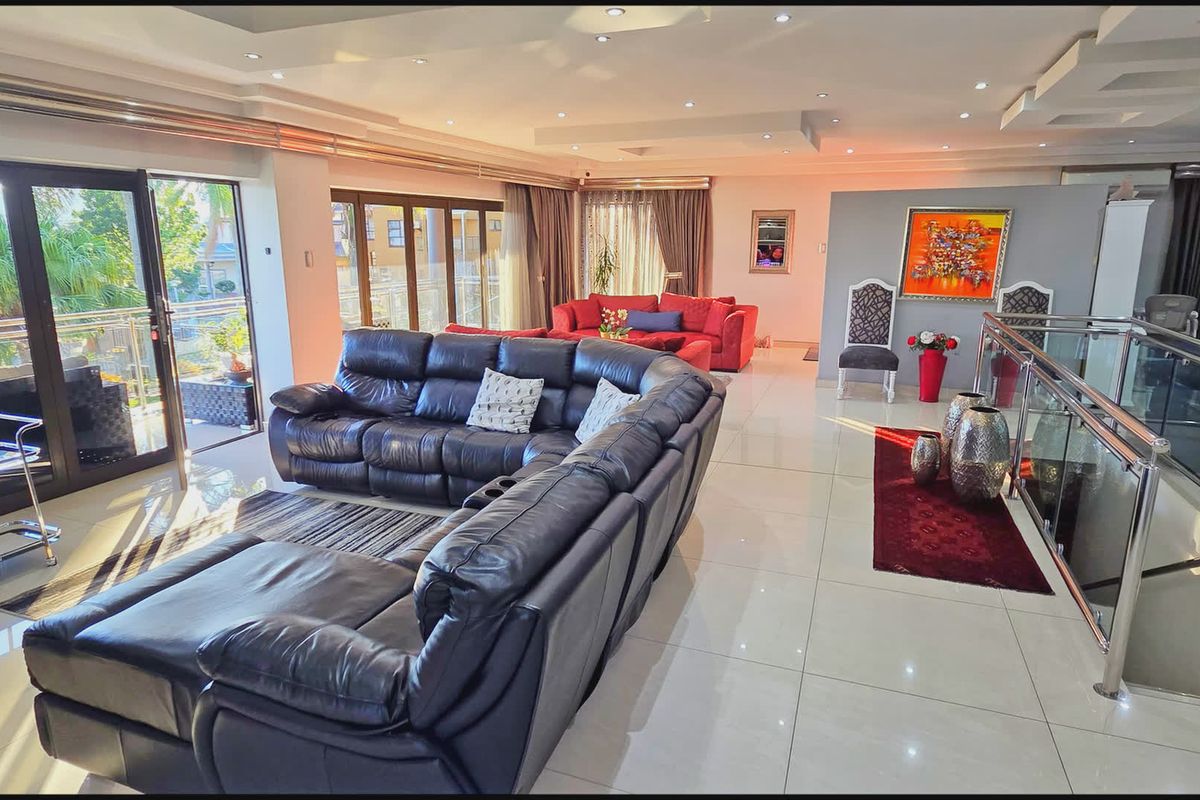 Spacious open-plan living area featuring polished tile flooring, recessed ceiling lighting, and large sliding glass doors leading to an outdoor balcony.