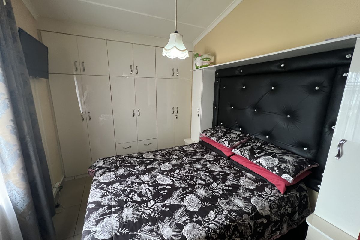 A bedroom featuring built-in high-gloss cabinetry and a fitted headboard unit, providing ample storage and a structured layout.