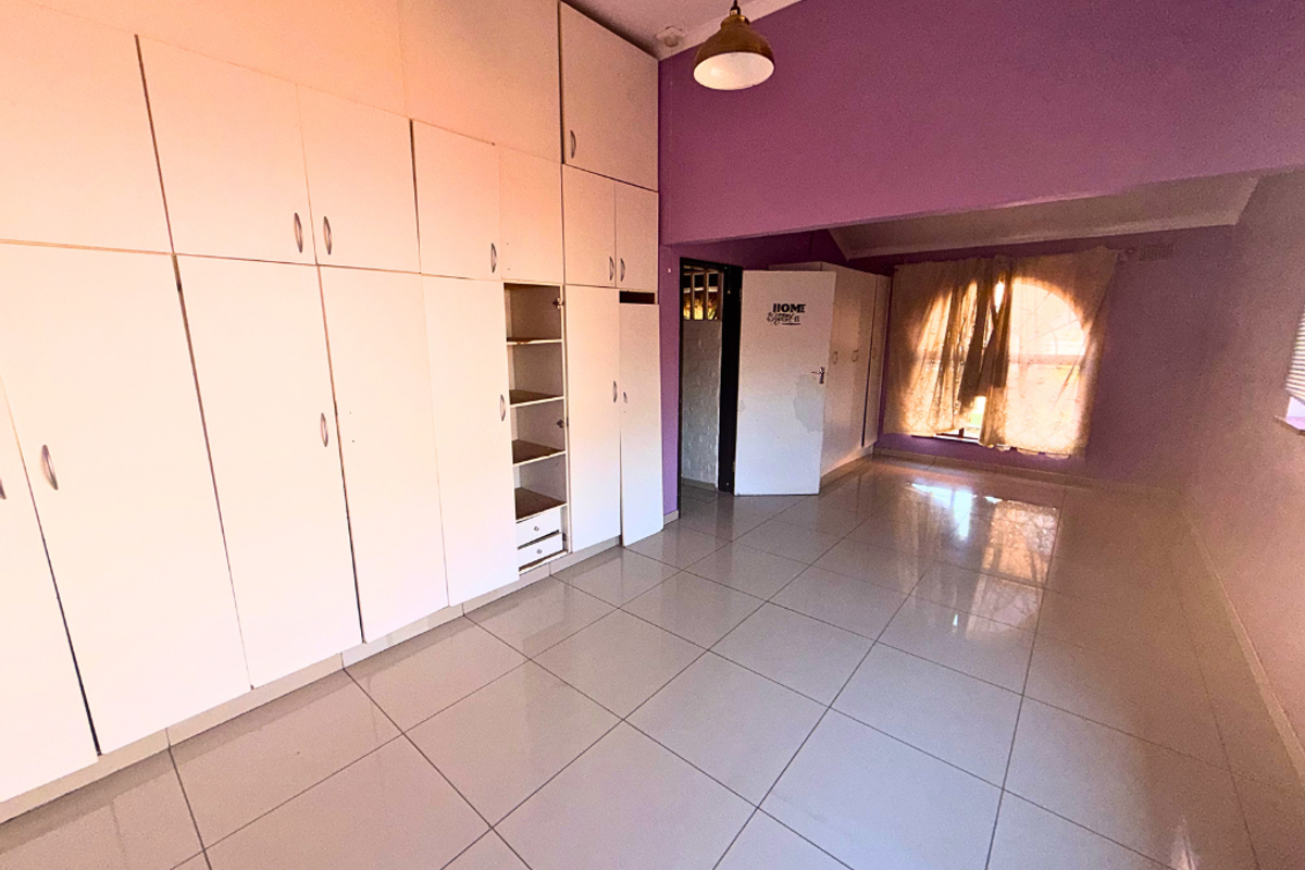 Spacious bedroom featuring extensive built-in cabinetry, tiled flooring, and a vaulted ceiling, offering ample storage and a bright, open layout.