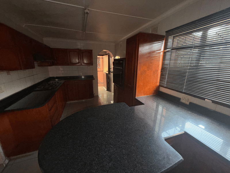 A functional kitchen featuring built-in wooden cabinetry, granite countertops, a built-in oven, and a gas hob, offering a solid foundation for modern updates.