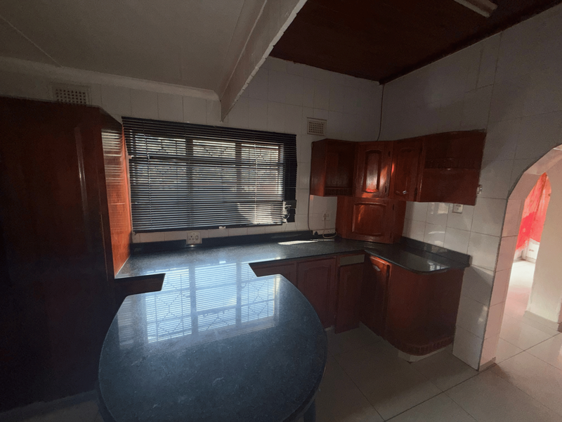 A functional kitchen featuring dark wood cabinetry, granite countertops, and tiled splashbacks, offering a classic layout ready for modern updates.