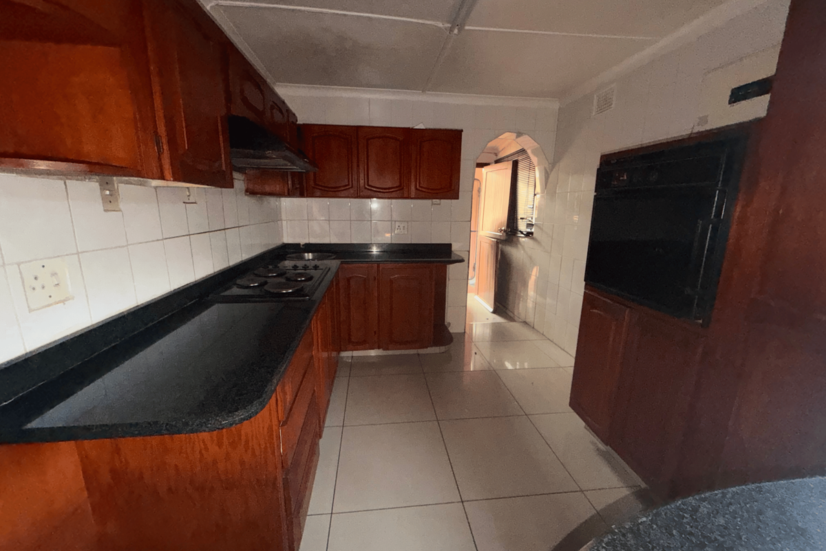 A dated kitchen featuring dark wood cabinetry, black granite countertops, built-in oven, and tiled finishes, offering significant potential for a modern renovation.