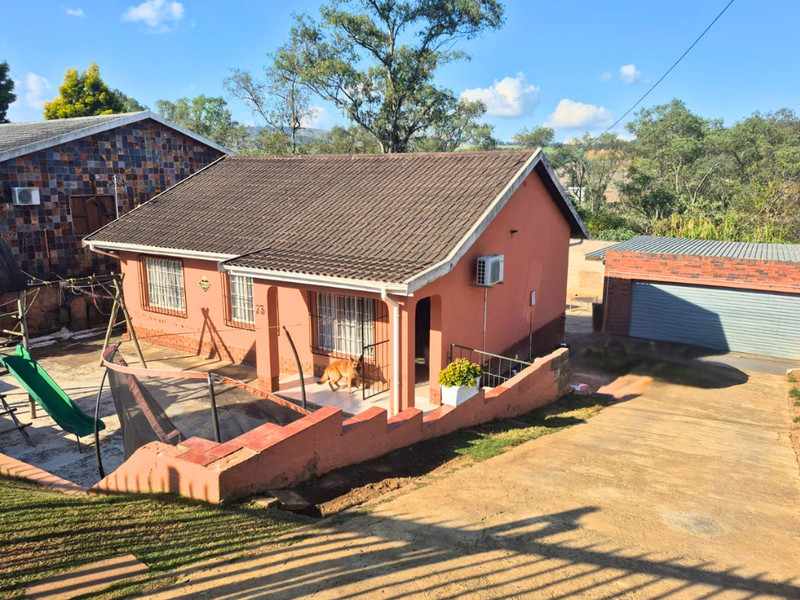 A detached single-story house featuring a tiled roof, covered entrance porch, and a paved driveway leading to a separate garage structure.