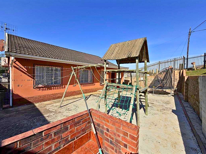 Rear exterior view of the house featuring a paved courtyard area, brick boundary wall, and tiled roof structure.
