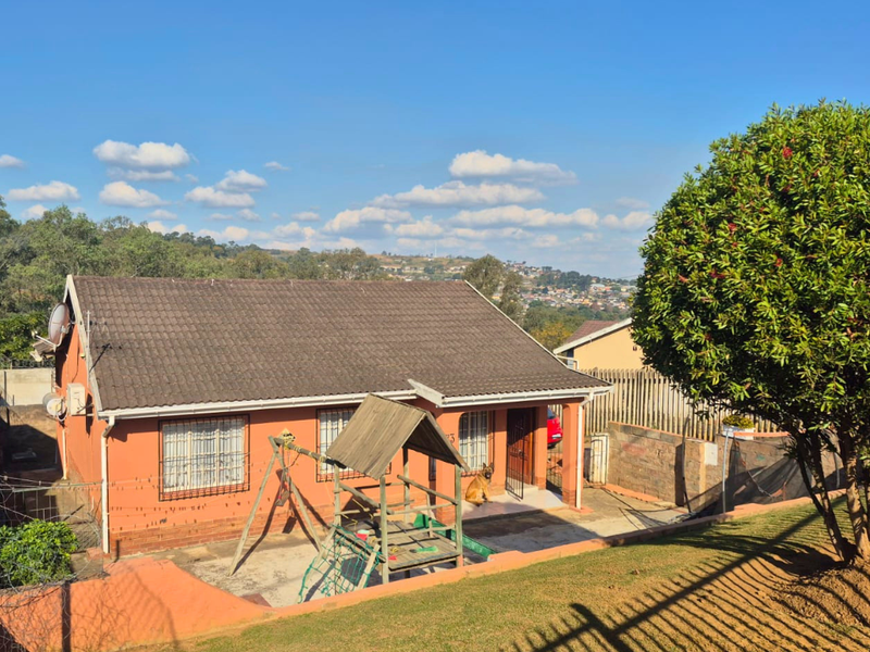 A detached residential house featuring a tiled roof, security bars on windows, and a paved front patio area with a garden.