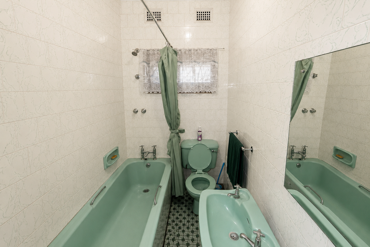 A compact, vintage-style bathroom featuring a pastel green bathtub, matching pedestal basin, and toilet, complemented by full-height wall tiling.