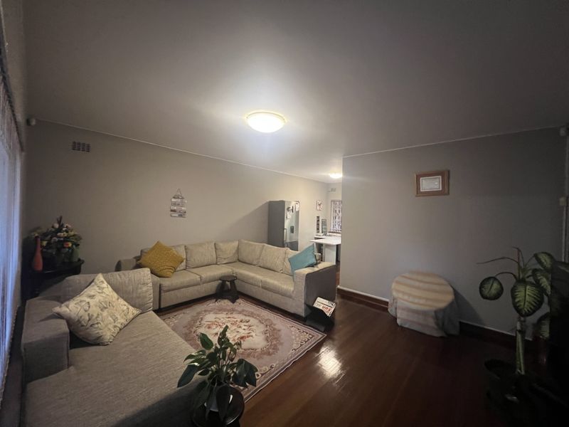 A spacious open-plan living area featuring polished timber flooring and neutral wall tones, providing a comfortable and versatile layout for daily living.