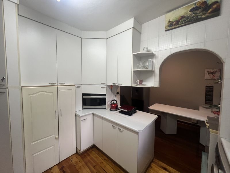 A functional kitchen featuring white cabinetry, built-in microwave space, and an arched opening leading to an adjacent dining or living area.