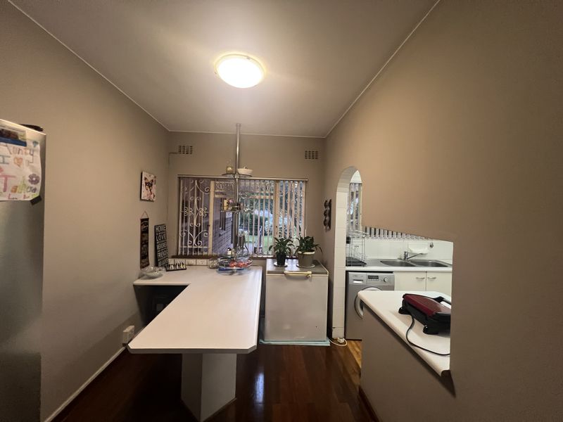 A functional kitchen area featuring a breakfast bar, built-in cabinetry, and a pass-through window connecting to the adjacent laundry or scullery space.