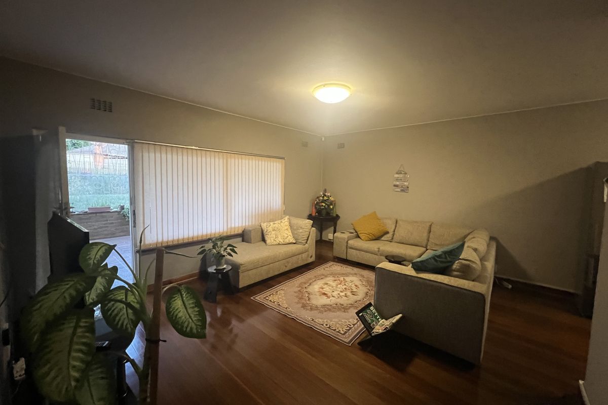 Spacious living room featuring polished timber flooring and large sliding glass doors providing direct access to the outdoor patio area.