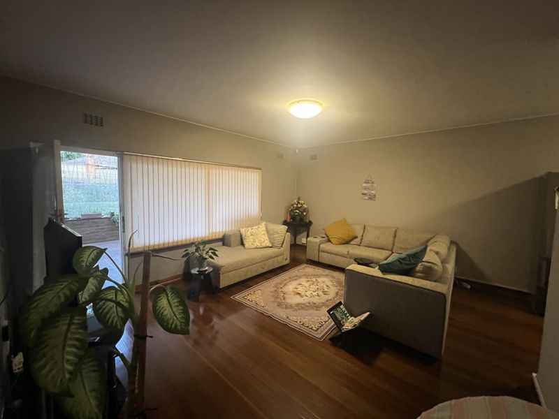 Spacious living room featuring polished timber flooring and large sliding glass doors providing direct access to the outdoor patio area.