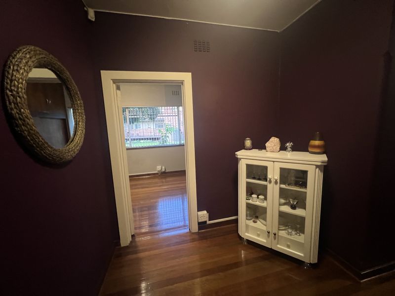 A view through a doorway into an adjacent room, featuring dark painted walls and polished timber flooring.