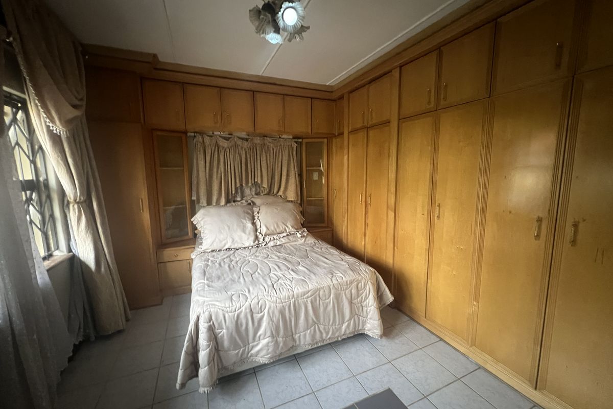 A bedroom featuring extensive built-in wooden cabinetry and storage units surrounding the bed area, with tiled flooring and a ceiling fan.