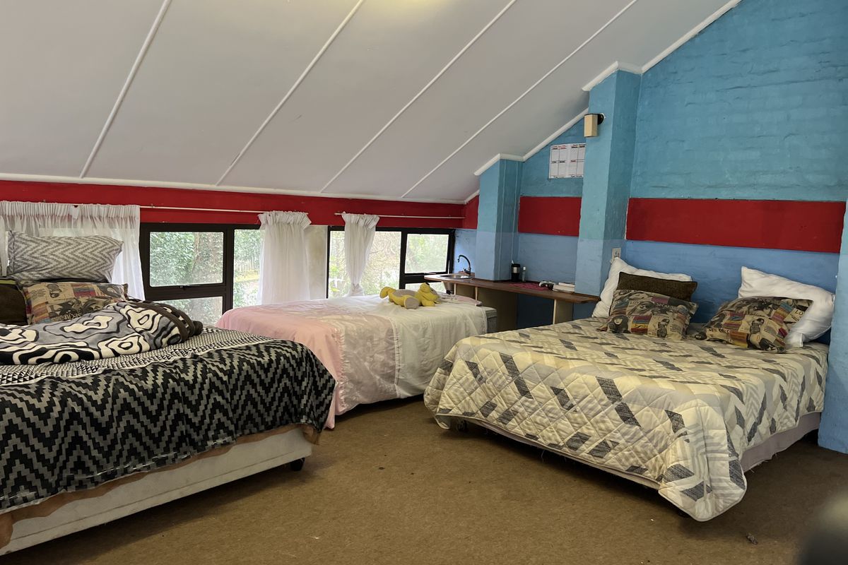 Spacious bedroom featuring a sloped ceiling, built-in vanity area with sink, and large windows allowing natural light.