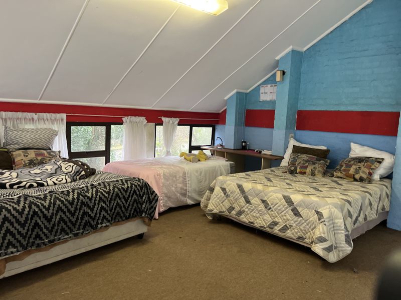 Spacious bedroom featuring a sloped ceiling, built-in vanity area with sink, and large windows allowing natural light.