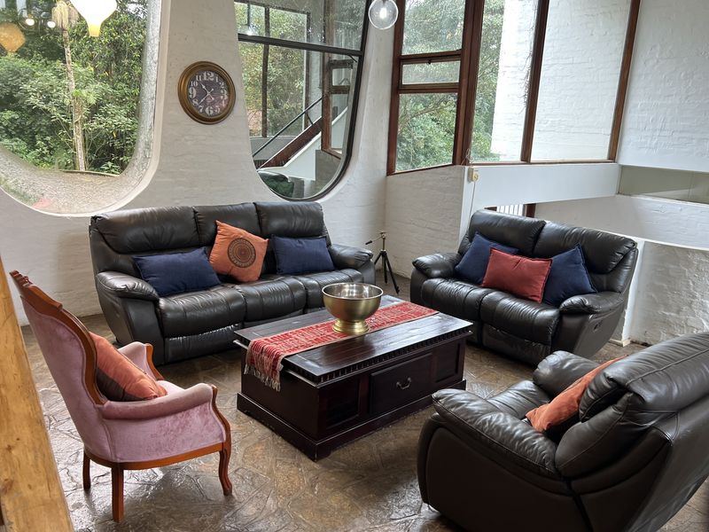 Spacious living area featuring unique architectural curved windows, exposed white brick walls, and natural stone flooring with abundant natural light.