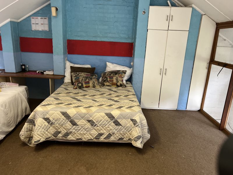 Bedroom featuring built-in white cabinetry, sloped ceilings, and carpeted flooring, offering a functional space with potential for cosmetic updates.