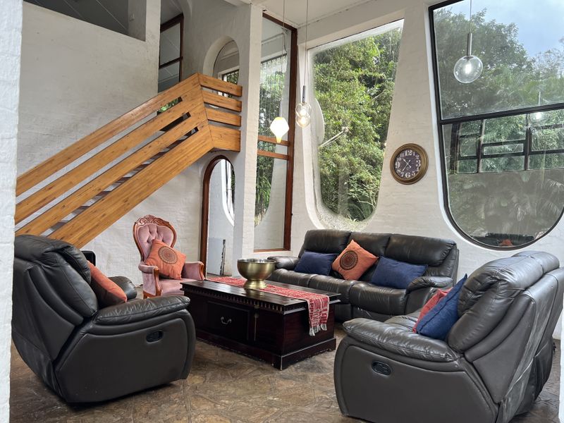 Spacious living room featuring unique architectural design, large floor-to-ceiling windows, and a wooden staircase leading to an upper level.