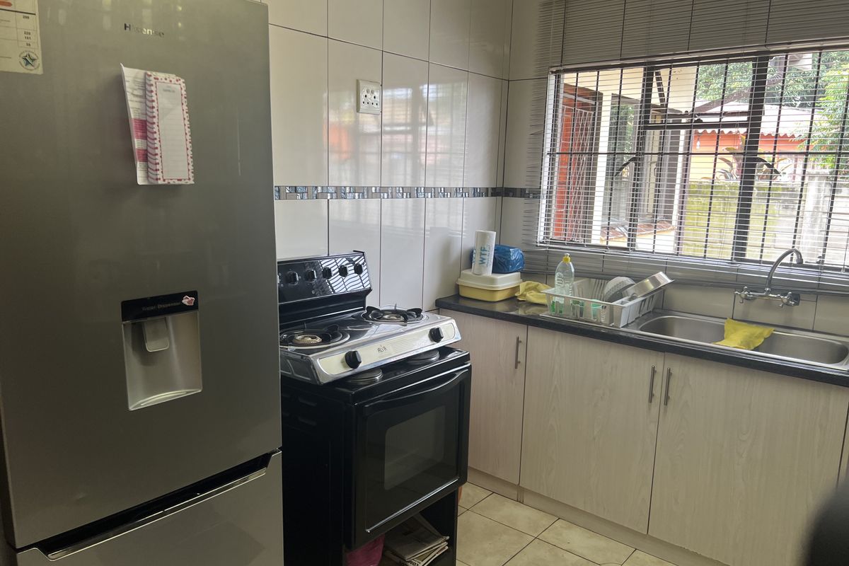 A functional kitchen featuring tiled walls, built-in cabinetry, a stainless steel sink, and a freestanding gas stove.