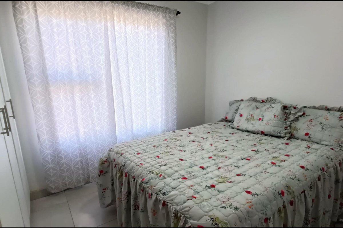 A functional bedroom featuring built-in cupboards and tiled flooring, providing a clean and neutral space.