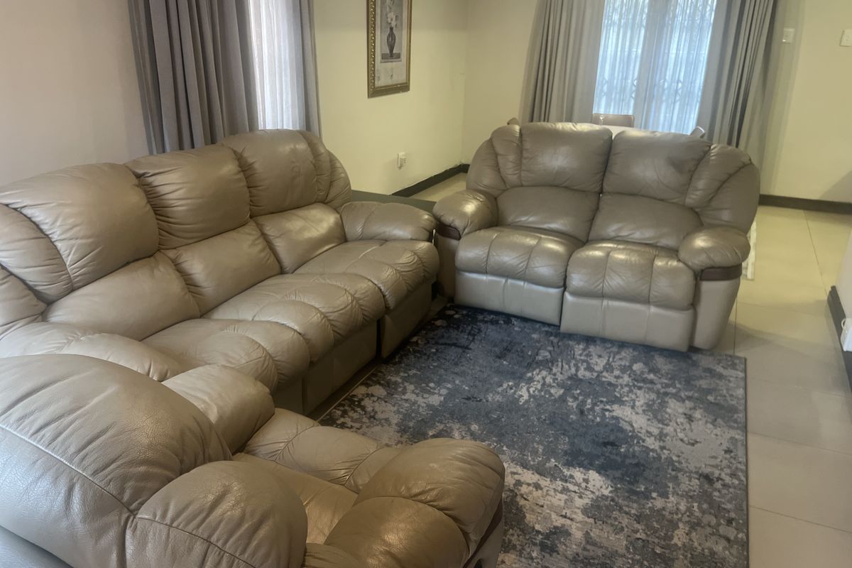 A comfortable living room area featuring tiled flooring and large windows with curtains, providing a bright and functional space for relaxation.