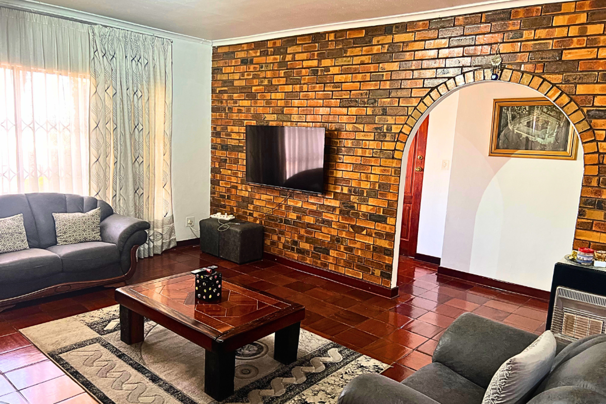 A living room featuring a prominent exposed brick feature wall with an arched doorway and traditional terracotta floor tiles.