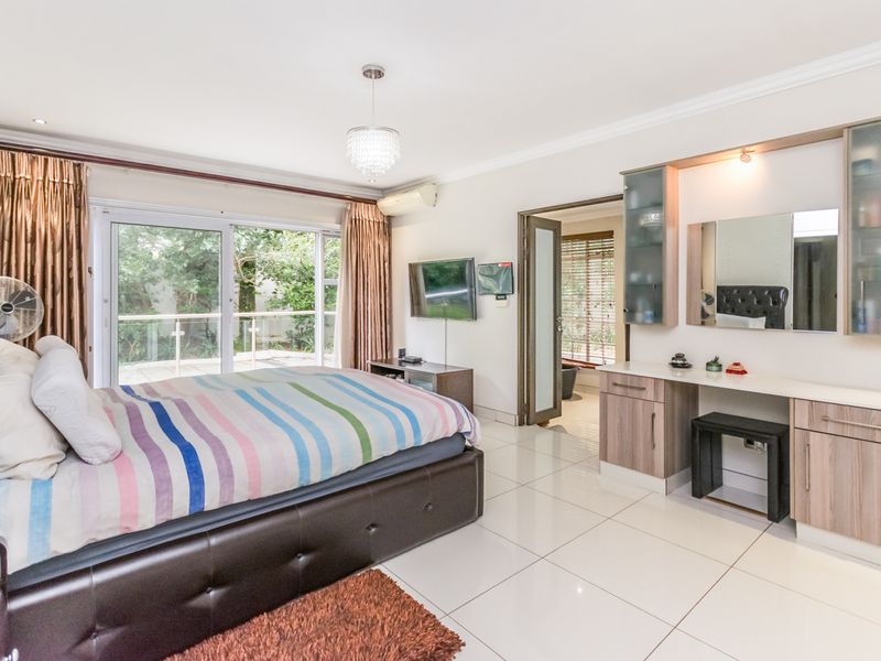 Spacious bedroom featuring tiled flooring, a built-in vanity unit, and large sliding glass doors providing access to an outdoor area.