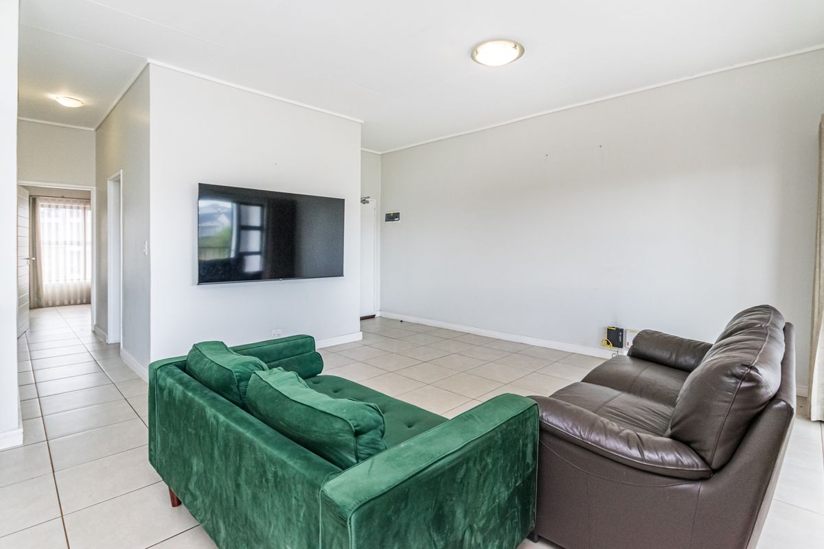 Spacious living area featuring neutral tiled flooring, recessed ceiling lighting, and a wall-mounted television point, offering a clean and functional layout.