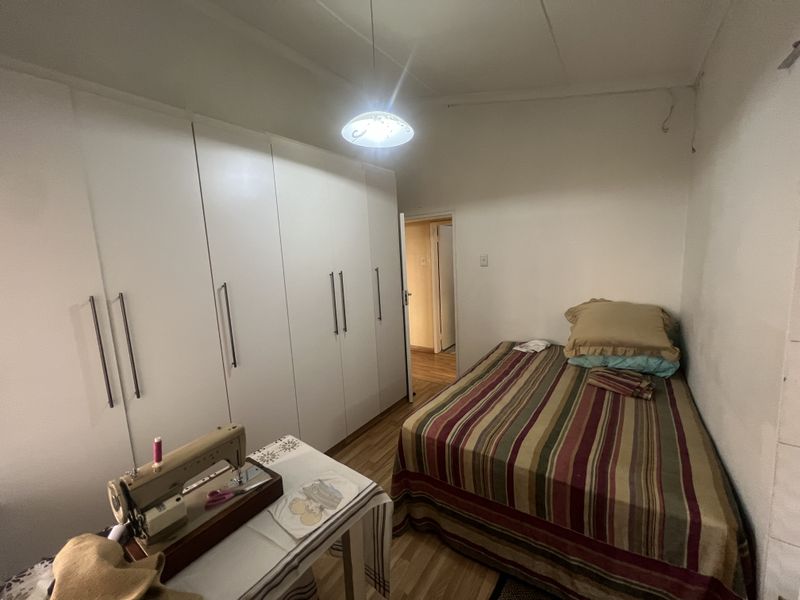 A functional bedroom featuring built-in floor-to-ceiling wardrobes and wood-look flooring, providing ample storage space.